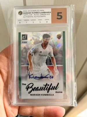 FIFA autografkort Marash Kumbulla - Samlarkort från 2022-23 Donruss FIFA med Marash Kumbulla i Roma-tröja. Kortet har autograf och holografisk yta, graderat av Professional Card Grading med betyg 5. Kortet är inplastat och har texten 'The Beautiful Game'.