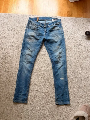 Dondup herr jeans  - Säljer ett par blå dondup jeans med slitningar och distressed detaljer. Jeansen har klassisk femficksmodell och dragkedjegylf. Perfekta för en avslappnad stil och passar till det mesta i garderoben.