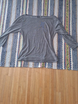 Grå topp från Fransa med 3/4-ärm - Snygg grå topp från Fransa med 3/4-ärm och rund halsringning. Tunn och mjuk kvalitet som sitter skönt på kroppen. Perfekt till jeans eller kjol för en enkel och clean look.