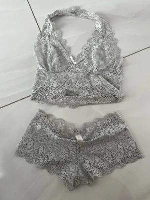 Vintage Victoria Secret set - Säljer ett superfint vintage grått spetsset från Victoria Secret. Setet har ett detaljerat spetsmönster och vågiga kanter som ger en romantisk vibe. Materialet är mjukt och stretchigt för extra komfort. Perfekt för dig som vill ha något både snyggt och bekvämt.