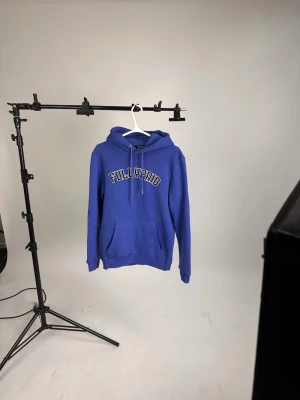Blå hoodie med tryck från Fullypaid - Snygg blå hoodie från Fullypaid med stor magficka och huva med dragsko. Trycket 'FULLYPAID' i vitt och svart på bröstet ger en clean streetwear-look. Perfekt för dig som gillar avslappnad stil och vill ha något bekvämt och trendigt.