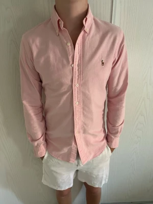 Ralph Lauren skjorta rosa slimfit - Rosa slimfit Ralph Lauren skjorta Märke: Ralph Lauren Storlek: S Passform: Slimfit Färg: Rosa Skick: Mycket bra, en liten grå fläck på insidan av ena ärmen som nästan är osynlig, syns inte vid användning pga att den sitter på insidan Nypris: 1800 SEK Modellen på bilden: 184CM och väger 76KG