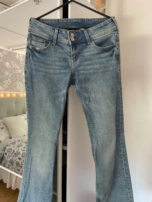 Blå bootcut jeans med broderade fickor från hm - Snygga blå bootcut jeans med dubbla knappar i midjan och broderade detaljer på bakfickorna. Jeansen har klassisk femficksmodell och är tillverkade i ett mjukt denimtyg med lätt tvättad look. Perfekta för dig som gillar en retrostil. På tredje bilden visar jag bakfickan så ha det i åtanke😊