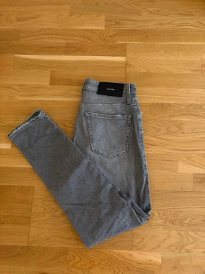 Gråa Calvin Klein jeans - Snygg grå färg på dessa Calvin Klein jeans. Slim fit modell, storlek 30/32