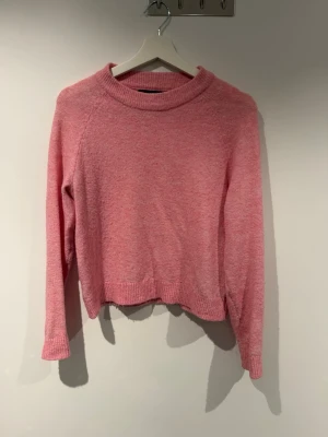 Rosa stickad tröja med rund hals - Mysig rosa stickad tröja med rund halsringning och långa ärmar. Tröjan har ribbstickade muddar vid ärmslut och nederkant samt en avslappnad passform. Perfekt för dig som gillar en enkel men snygg look. Material: Polyester, Acrylic, Wool och Elastane. 