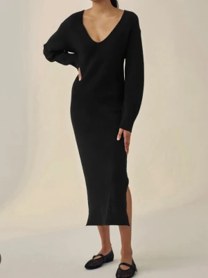 Svart ribbad långklänning - Svart långklänning i ribbat material med v-ringning och långa ärmar. Klänningen har en slits på sidan och en figurnära passform som ger en stilren och modern look. Perfekt för dig som gillar minimalistisk stil.