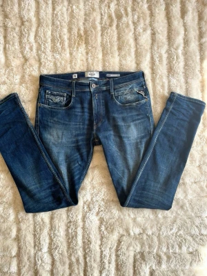 Replay Anbass jeans i blå - stl 34/36 (L) - Replay Anbass jeans i blå, storlek 34/36 (L). Slim passform med lång benlängd och ljusare partier på lår och knän. Funkar året runt.  Använd men i mycket fint skick, inga hål eller fläckar.  Rök- och djurfritt hem. Skriv gärna om du vill ha fler bilder eller undrar något!