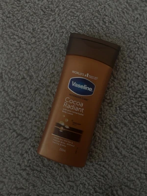 Vaseline Cocoa Radiant Body Lotion - Vaseline Intensive Care Cocoa Radiant Body Lotion med ren kakaosmör. Flaskan är brun med brunt lock och rymmer 200 ml. Perfekt för att återfukta torr hud och ge naturlig lyster utan att kännas fet.