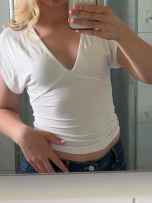 Vit omlottopp med v-ringning - !!!stor i storleken, har i vanliga fall M men XS passar i denna!!!!                                                   Säljer en vit omlottopp med v-ringning och korta ärmar. Toppen är figurnära och har en croppad passform som passar perfekt till höga jeans eller kjol. Enkel och stilren design som är lätt att matcha.