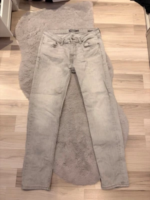 Ljusgrå slim fit jeans Dressmann - Säljer ett par ljusgrå slim fit jeans från Dressmann. Jeansen har klassisk femficksdesign, raka ben och är tillverkade i ett mjukt denimtyg. Perfekta för dig som gillar en clean och enkel stil.