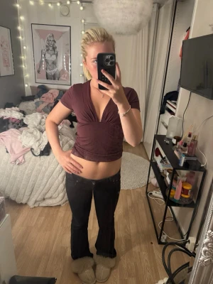 Mörkröd croppad v-ringad topp - Snygg mörkröd croppad topp med djup v-ringning och korta ärmar. Toppen har en figurnära passform och är tillverkad i ett mjukt, stretchigt material som sitter bekvämt mot kroppen. Perfekt för dig som vill ha en trendig och enkel look.