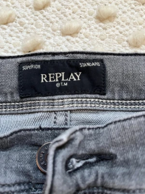 Grå jeans från Replay Wallys - Snygga grå jeans från Replay, modell Wallys. Klassisk femficksdesign med knappgylf och raka ben. Jeansen har en cool tvättad look och är tillverkade i ett mjukt och slitstarkt denimtyg. Perfekta för dig som gillar stilrena och tidlösa jeans.