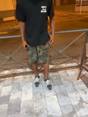 Camo cargoshorts med fickor - Säljer ett par camouflagemönstrade cargoshorts med flera praktiska fickor och snörning i midjan. Perfekta för en avslappnad streetwear-look och passar till både sneakers och t-shirt.