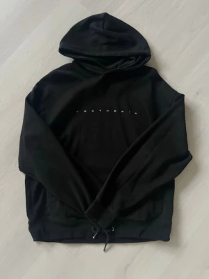 Svart hoodie från Bershka - Snygg svart hoodie från Bershka med minimalistiskt tryck 'YOUTHORIA' på bröstet. Klassisk huva och dragsko nedtill. Tillverkad i mjukt bomullsmaterial som är skönt att bära. Perfekt för en avslappnad och trendig look.