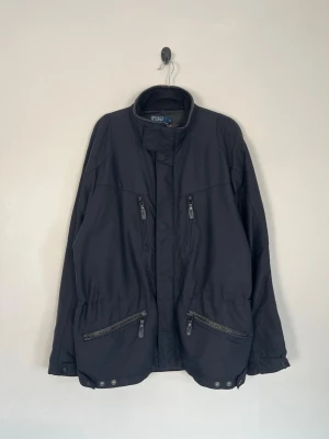 Vintage Polo Ralph Lauren Field Jacket - • Storlek: M • Färg: Svart • Passform: Regular Fit • Krage: Hög ståkrage med mjukt fleecefoder • Material: Yttertyg: 100 % nylon, Foder 100% polyester, Fyllning 100 % polyester  Skick: Plagget är i väldigt fint skick. Eventuella anmärkningar anges alltid tydligt i beskrivningen och visas på bilderna.  Nypris: Cirka 4 000 kr.  📦 Skickas snabbt och packas omsorgsfullt. 💬 Hör gärna av dig om du har frågor eller vill se fler bilder. 🤝 Samfrakt erbjuds vid köp av flera plagg – kika gärna in mina andr