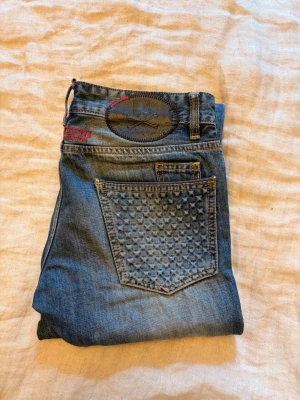 Philipp Plein XVIII Edition jeans - Philipp Plein XVIII Edition jeans 🔥  Snygga Philipp Plein jeans från XVIII Edition med den ikoniska skull-detaljen och karakteristiska detaljer på bakfickorna.  Riktigt fet denim med snygg washed/vintage-look och många detaljer. Ett par jeans som verkligen sticker ut.   Fint begagnat skick med naturlig användningskänsla.