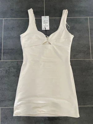 Beige kort tajt klänning  - Jättefin beige kort tajt klänning från Zara som tyvärr aldrig kommit till användning. Helt ny med prislapp.