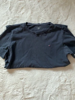 Svart t-shirt från Tommy Hilfiger - En stilren svart t-shirt från Tommy Hilfiger med klassisk rund hals och liten broderad logga på bröstet. Perfekt basplagg som funkar till det mesta och är gjord i mjuk bomull för skön känsla.