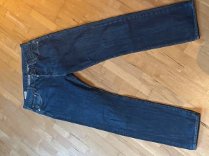 Mörkblå raka jeans - Säljer ett par klassiska mörkblå jeans med rak passform och fem fickor. Jeansen har normal midja och stängs med dragkedja och knapp. Perfekta till en avslappnad stil och funkar året runt.