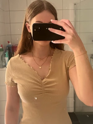 Beige ribbad topp med v-ringning - Säljer en beige ribbad topp med korta ärmar och v-ringning.  Från NAKD. I storlek S.
