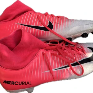 Nike Mercurial Victory VI DF AG-Pro - Säljer ett par Nike Mercurial fotbollsskor i en snygg rosa och vit färg med svarta detaljer. Skorna har högt skaft i stretchigt material, snörning och klassisk Nike-logga på sidan. Perfekta för dig som vill sticka ut på planen! Skorna är anpassade till användning på konstgräs. Har använt de ett par gånger sen dess aldrig. Priset är inte hugget i sten heller