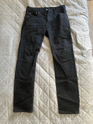 Svarta slim fit jeans - Säljer ett par svarta slim fit jeans med klassisk femficksdesign och silverfärgade nitar. Jeansen har normal midja och raka ben. Jeansen har lite stretch för extra komfort. Perfekta till en avslappnad look. W29/L32