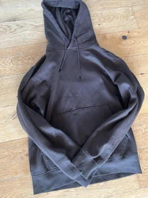 Brun hoodie från Jack & Jones - Snygg brun hoodie från Jack & Jones med klassisk känguruficka och justerbar huva med dragsko. Tillverkad i mjukt bomullsmaterial som känns skönt mot huden. Perfekt för en avslappnad och trendig look. Storlek S
