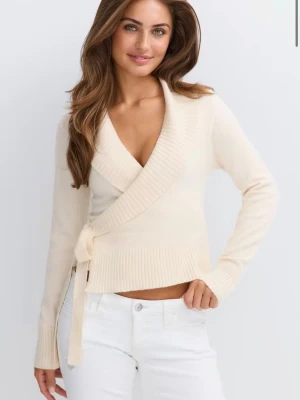Beige omlottstickad tröja - Säljer en beige stickad omlott-tröja med knyt i sidan och bred ribbad kant. Tröjan har djup v-ringning och långa ärmar. Perfekt för dig som gillar en enkel men snygg look. Gina Tricot. 