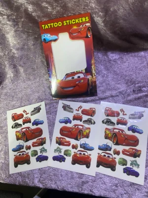 Tatueringsstickers med Bilar-motiv - Säljer ark med tatueringsstickers som har motiv från filmen Bilar. Flera olika färgglada bilar i rött, blått, grönt och lila. Perfekt för dig som gillar Disney och vill ha roliga tillfälliga tatueringar. Kommer i förpackning med tre ark. Finns fler kvar 