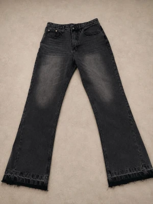 Svarta raka jeans med rå kant - Säljer ett par svarta jeans med rak passform och rå, fransig kant längst ner. Jeansen har klassisk femficksmodell och subtila slitningar framtill för en cool vintagekänsla. Perfekta för dig som gillar en avslappnad och trendig stil.