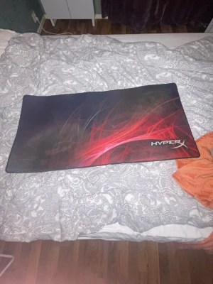 HyperX stor gaming musmatta - Säljer en stor gaming musmatta från HyperX med svart bas och röd grafik. Mattan har rektangulär form och är tillverkad i tyg med gummerad undersida för bra grepp. Perfekt för gaming setupen och ger mycket plats för både mus och tangentbord.