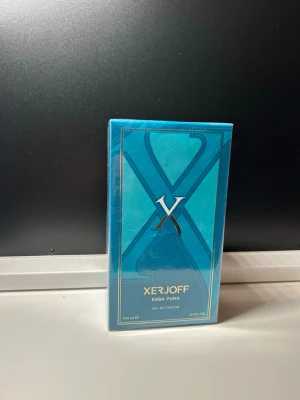 Xerjoff Erba Pura Eau de Parfum 100ml - Xerjoff Erba Pura Eau de Parfum i en elegant blå förpackning med gulddetaljer. Flaskan rymmer 100 ml och doften är känd för sina fruktiga och fräscha noter. Lyxig design som passar perfekt för dig som gillar exklusiva parfymer.
