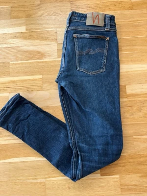 Nudie Jeans - W30 L32 - Snygga mörkblå jeans från Nudie Jeans. Klassisk och stilren modell med snygga kontrastsömmar och ikonisk Nudie-detalj på bakfickan.  📏 Storlek: W30 L32 🎨 Färg: Mörkblå 👖 Passform: Slim/straight ✨ Skick: Mycket fint skick, inga tydliga skador eller hål