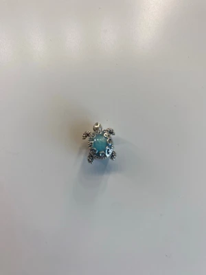 Havssköldpadda berlock i silverfärg med lite blått - Berlock formad som en havssköldpadda i silverfärgad metall med en ljusblå sten i mitten. Perfekt att hänga på ditt ex Pandora armband