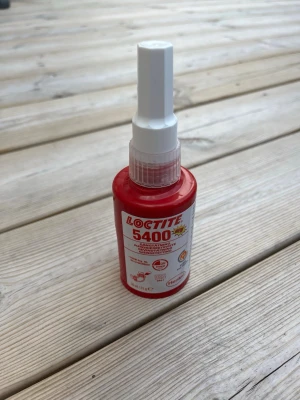 Loctite 5400 tätning - Loctite 5400 tätningsmedel i röd plastflaska med vit etikett och applikator. Används för att täta gängor och rör inom industri och verkstad. Flaskan har tydlig märkning och symboler för användningsområden.