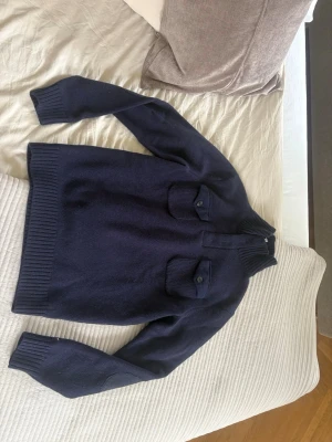 Jättefin herr Tommy Hilfiger mörkblå stickad tröja med krage  - Jättefin Tommy Hilfiger mörkblå stickad tröja med krage som är perfekt nu till hösten. Den är i storlek L, är i mycket bra skick, inga skavanker eller nått sånt. Tröjan är väldigt varm och skön, den är unik och har så fina detaljer. Passformen är väldigt bra och materialet är 100% lambswool. Priset kan diskuteras, lämna gärna omdöme om köpt och priset kan diskuteras😊