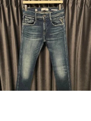 Blåa replay anbass  - Säljer ett par blå jeans med raka ben och snygga slitningar på låren och knäna. Jeansen har klassisk femficksdesign, kontrastsömmar och en cool tvättad look. Perfekta för dig som gillar en avslappnad men trendig stil. (W30,L32)