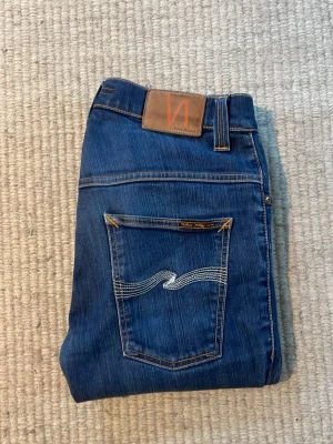 Blå skinny jeans från Nudie Jeans - Säljer nu ett par nudie jeans i modellen thin finn! En härlig och mjuk modell, en fin, lätt sliten tvätt som ger de en snygg vintagekänsla. Tydliga men diskreta ljusare partier/fades över lår och sömmar, vilket ger en levande denimlook. W31 L32! Se bilder för skick! 