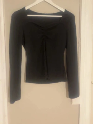 Svart långärmad topp med snörning - Trendig svart långärmad topp. Toppen passar allt från Xs till M och är väldigt skön och stretchig. Perfekt för dig som gillar stilrena plagg med en twist.