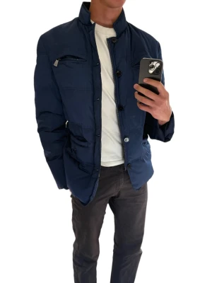 Mörkblå pufferjacka från trussardi - Snygg mörkblå pufferjacka från trussardi och knäppning framtill. Jackan har flera fickor med dragkedja och knappdetaljer, samt en modern, rak passform. Perfekt för kalla vinterdagar och ger en clean look till din outfit.