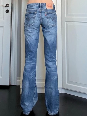 Bootcut jeans från Levi's  - Ett par bootcut jeans från Levi's med låg midja och fem fickor. Jeansen har en snygg wash och subtila slitningar. Aldrig använda av mig, riktigt bra skick. Lite slitna vid hälen på ena benet, annars saknar de defekter. Midjemått är 34cm rakt över och innerbenslängden är 84cm. Vid frågor eller önskemål om fler bilder är det bara att skriva privat. 💕