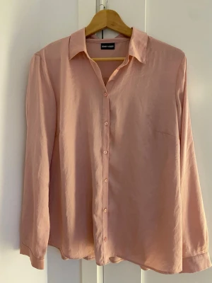 Ljusrosa skjorta från Gerry Weber - Stilren ljusrosa skjorta från Gerry Weber med klassisk krage och knäppning framtill. Skjortan har lång ärm och en avslappnad passform. Tillverkad i ett mjukt material som känns skönt mot huden. Perfekt att styla med jeans eller kjol.