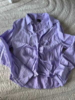 Ljuslila skjorta från Gina Tricot - Säljer en snygg ljuslila skjorta från Gina Tricot. Skjortan har klassisk krage, långa ärmar med knapp vid manschetten och knäppning framtill. Det skrynkliga framtill hör till men annars är den även lite skrynklig efter tvätten men annars i fint skick!!💕