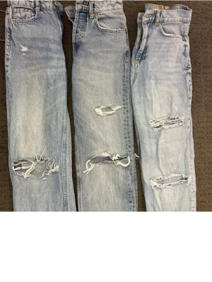 Ljusa slitna mom jeans med hål - Tre par ljusblå mom jeans med trendiga slitningar och hål på benen. Klassisk femficksmodell med hög midja och raka ben. Perfekta för en avslappnad streetwear-look. Jeans i denim med snyggt tvättad finish och råa detaljer.