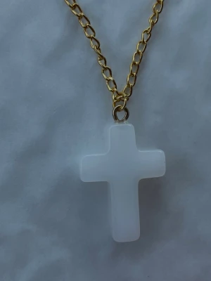 By prisförslag- Guldhalsband 55 cm med vit korsberlock - Snyggt halsband med en kedja i guldfärg och en vit korsformad berlock i plast eller resin. Kedjan har breda länkar som ger ett trendigt intryck och korset är stilrent och minimalistiskt. Perfekt accessoar för dig som gillar enkel men iögonfallande design.