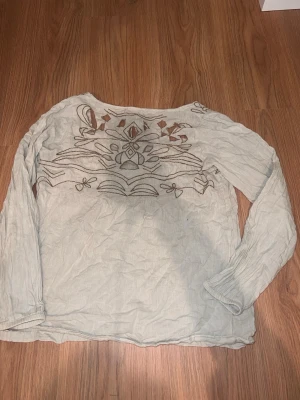 Beige broderad blus från Cream - Säljer en beige blus från Cream med långa ärmar och vackra broderade detaljer framtill. Blusen har ett bohemiskt mönster med utskurna partier och är tillverkad i ett tunt, luftigt tyg som ger en avslappnad känsla.