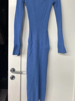 Blå ribbad långklänning - Snygg blå långklänning med ribbad struktur och lång ärm. Klänningen har en tight passform och är tillverkad i ett väldigt stretchigt material som sitter skönt på kroppen. Perfekt för dig som gillar en enkel men stilren look. 