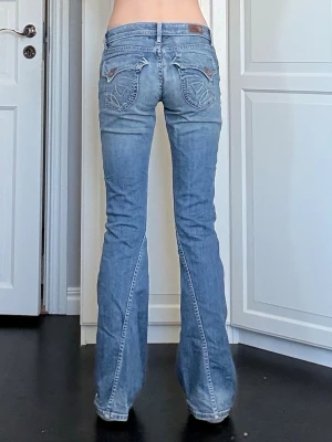 Blå bootcut jeans - Säljer ett par ljusblå bootcut jeans med riktigt coola broderade bakfickor. Jeansen har låg midja, fem fickor och är tillverkade i denim med lätt stretch. Sparsamt använda av mig, hela nere vid hälen och i bra skick. Midjemått på 36cm rakt över samt innerbenslängd på 84cm. Vid frågor eller önskemål om fler bilder är det bara att skriva privat 💕