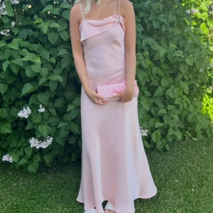 Rosa balklänning  -  Ljusrosa långklänning i satin med smala axelband och draperad detalj vid bysten. 🩷som man ser på bild 4 så tillkommer en sjal/scarf som man kan bära hur man vill om så önskas.🌟 Finns ingen utskriven storlek, men jag har vanligtvis S/36! Märket är ”Lulu H Paris”. 