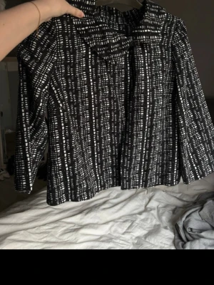 Trekvartsärmad jacka  - Trekvartsärmad jacka som man knäpper med en knapp vid halsen